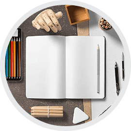 Modern workspace with stationery, open notebook, colored pencils, and design tools for creative projects.